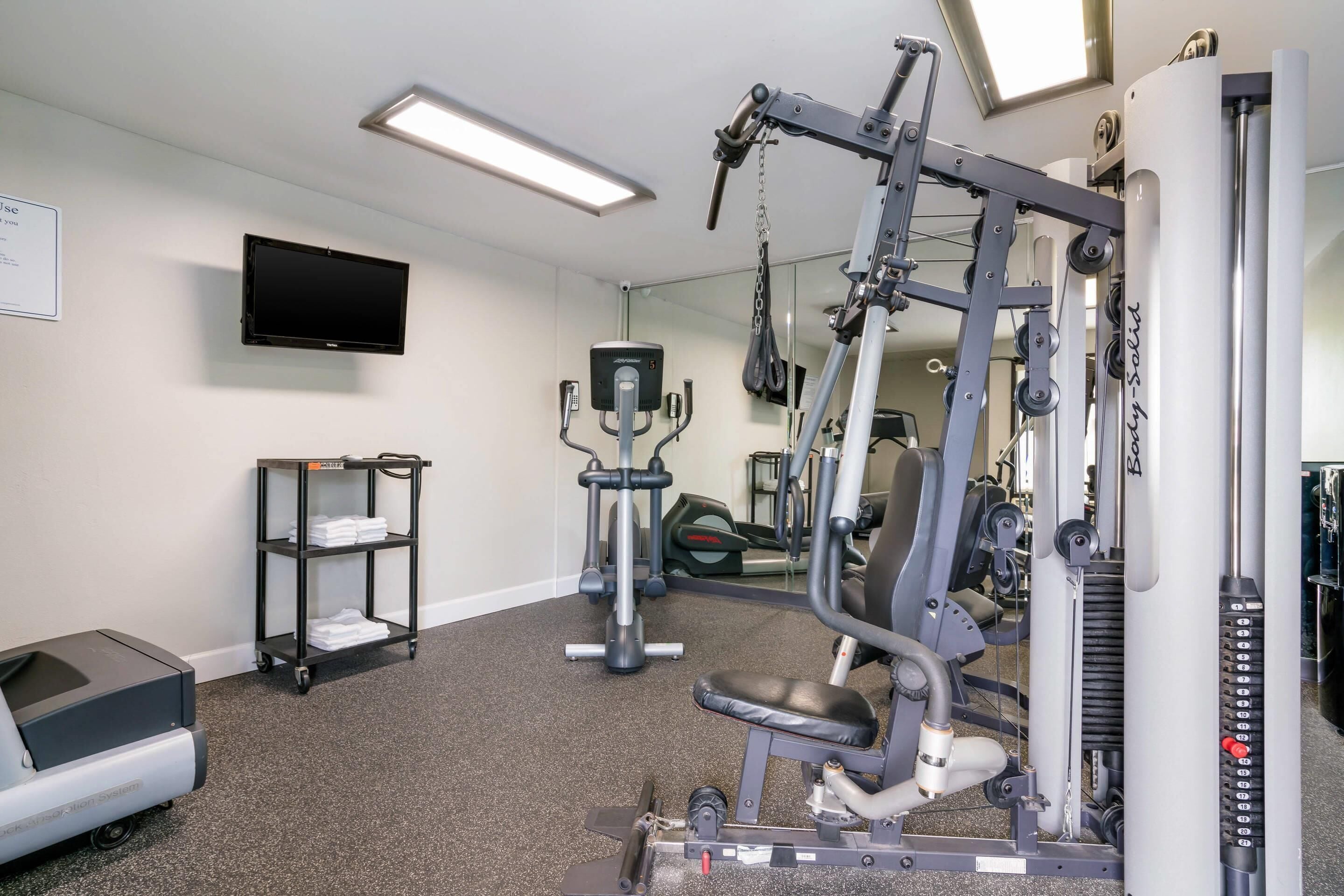 A gym with exercise equipment, a treadmill, and a mirror.