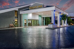 Quality Inn features a modern entrance with a glass door and pillars.