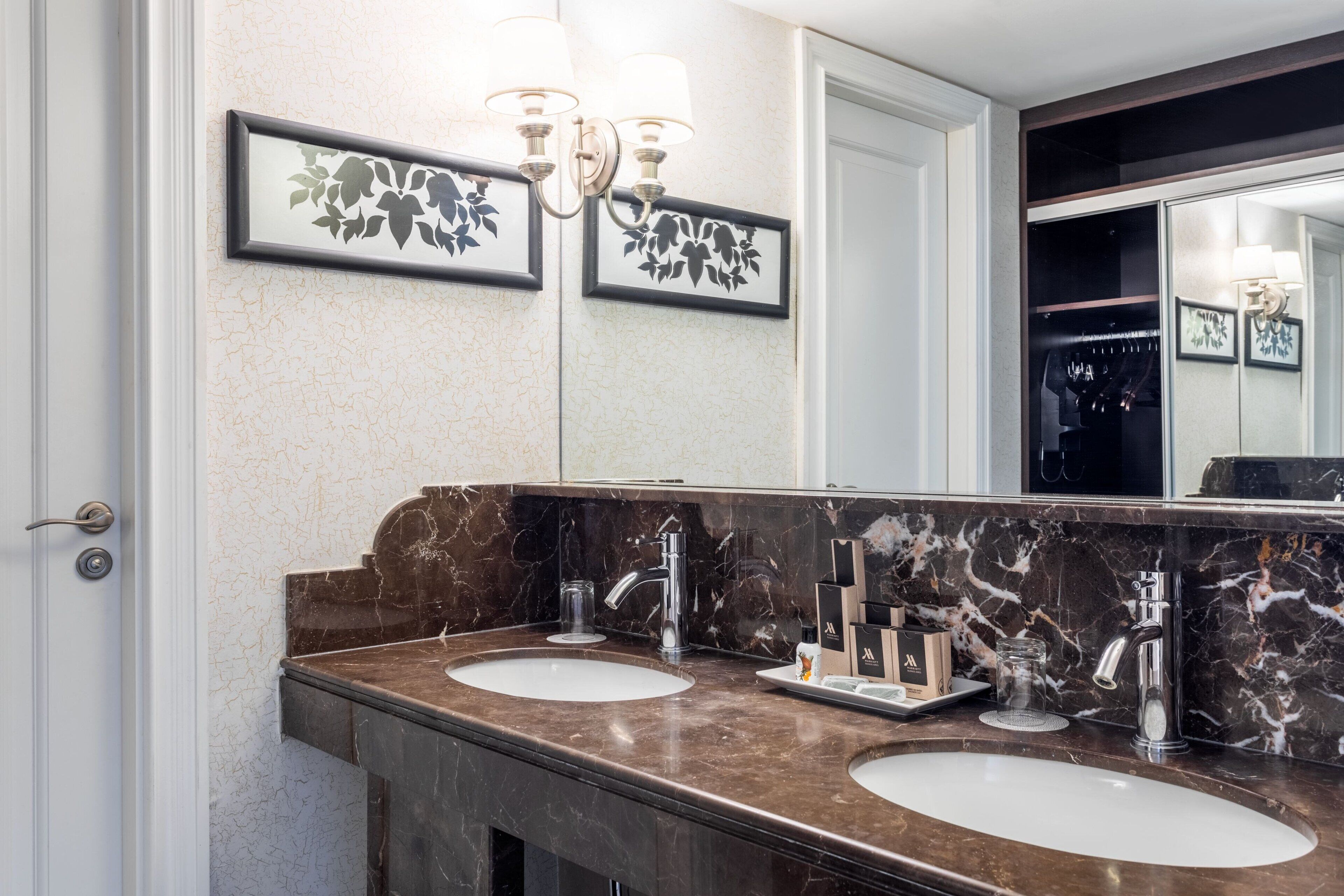 A bathroom with two sinks, marble countertops, and a large mirror.