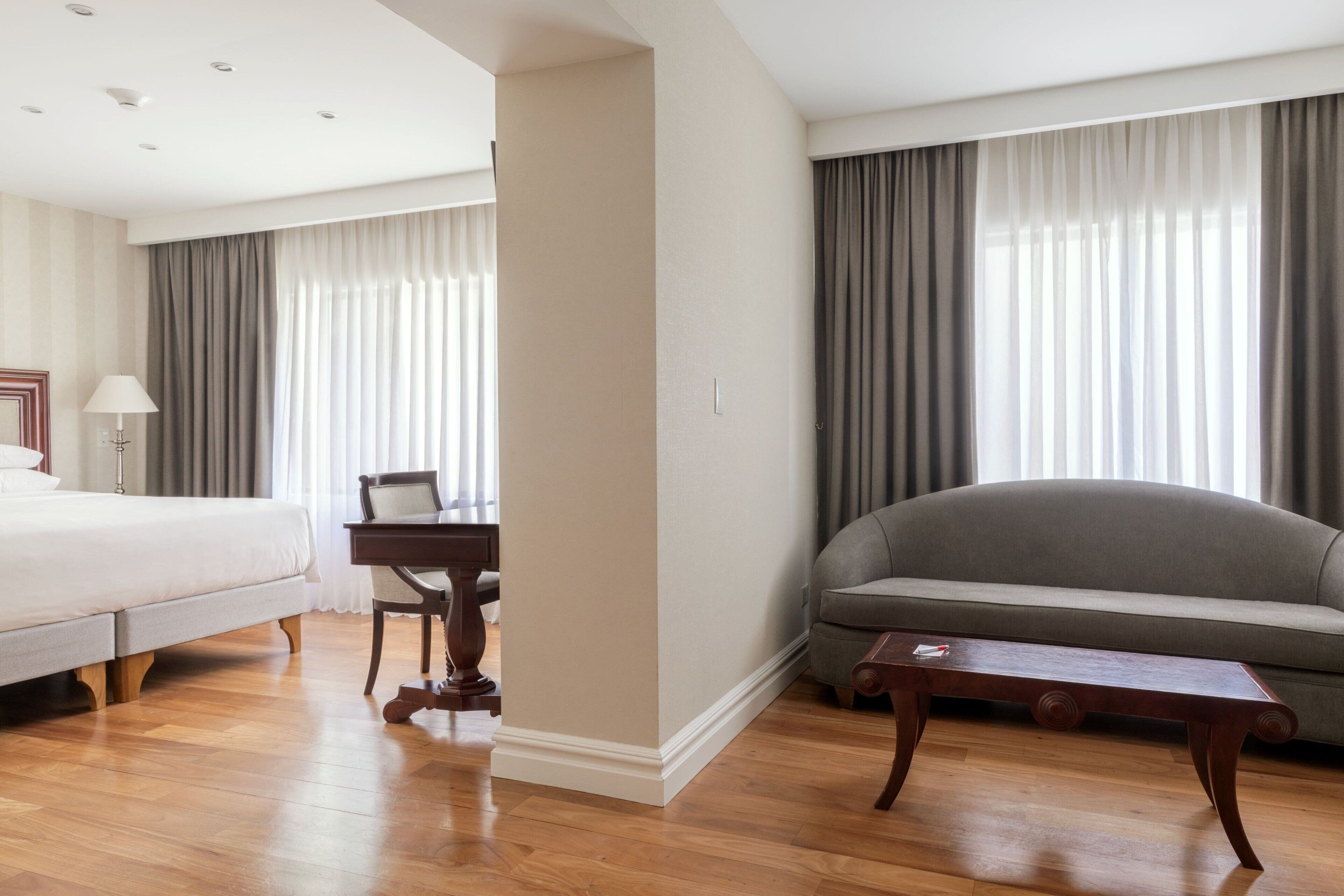 Ein Hotelzimmer mit einem Bett, einem Schreibtisch, einer Couch und einem Holztisch.
