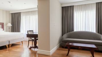 Une chambre d’hôtel avec un lit, un bureau, un canapé et une table basse en bois.