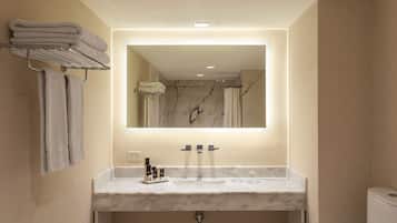 Un baño moderno con un lavabo de mármol, un espejo grande y un perchero para toallas.