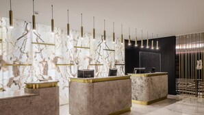 Un'accogliente area reception moderna con banconi in marmo e dettagli dorati, illuminata da luci a sospensione e con uno sfondo dai toni scuri.