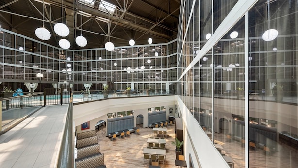 Un atrium à plusieurs niveaux, doté d’espaces de détente, d’une piscine et d’une façade en verre.
