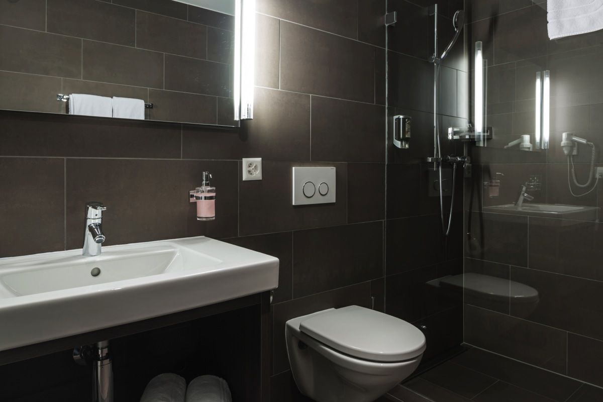 Ein modernes Badezimmer mit einem weißen Waschbecken, einer Toilette und einer Duschkabine.