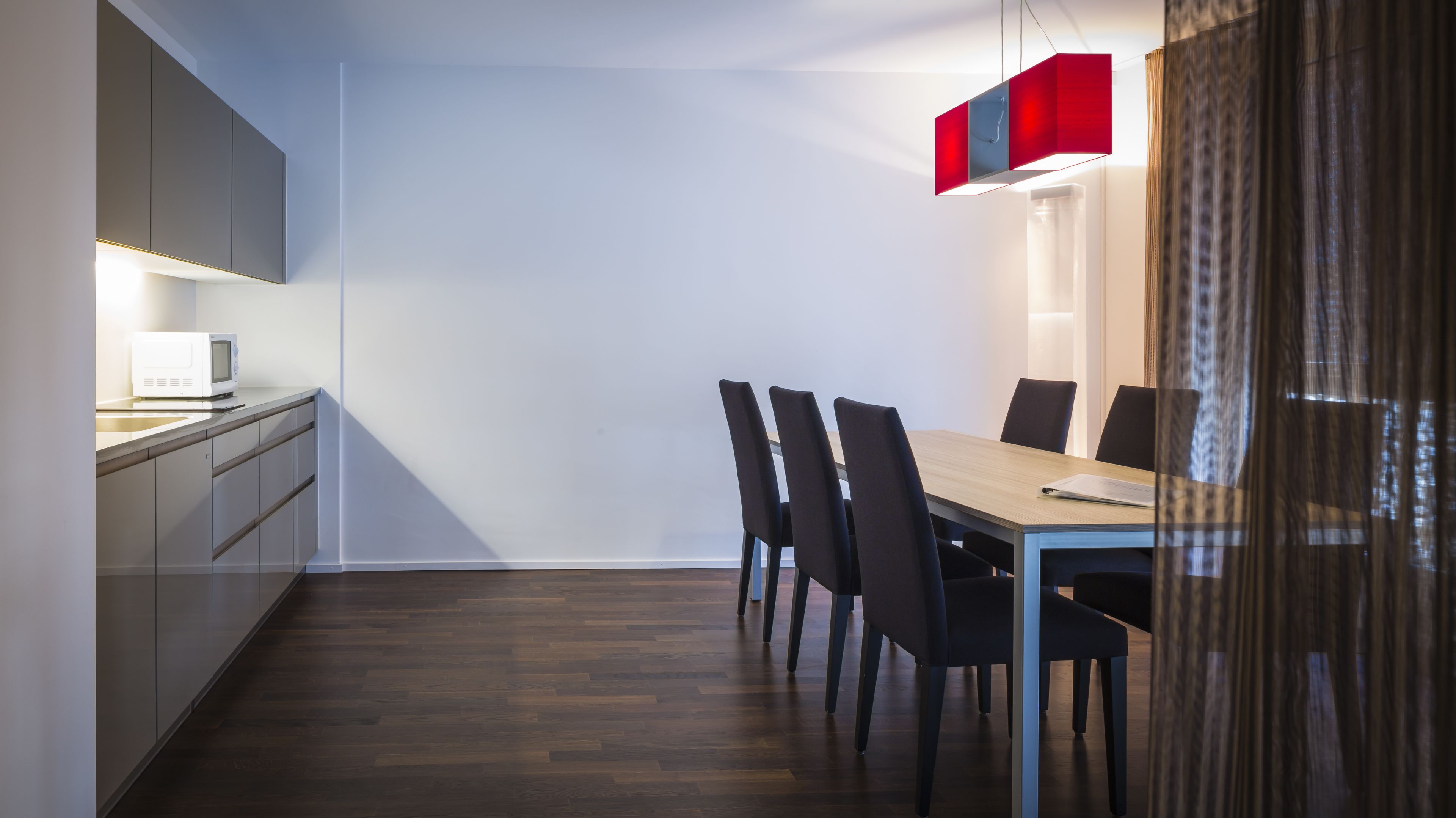 Uma cozinha moderna com micro-ondas, armários e uma área de refeições com mesa e cadeiras.