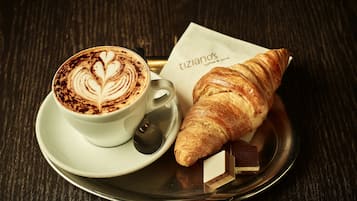 A cup of coffee with latte art and a croissant on a tray.