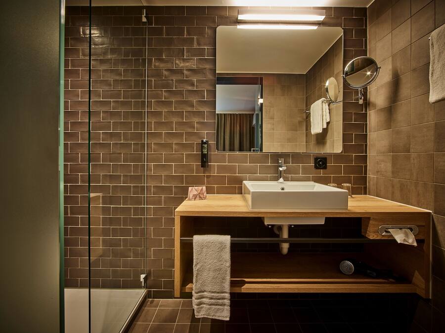 Un baño moderno con tocador de madera, un espejo grande y cabina de ducha de vidrio.