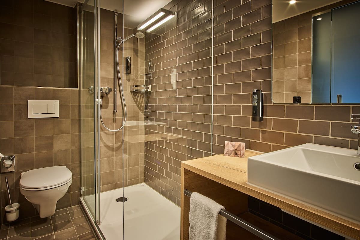 A modern bathroom with a glass-enclosed shower, a white toilet, and a wooden vanity with a sink.