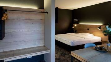 Une chambre d’hôtel comprenant un lit, un bureau, une chaise, une table de chevet, une lampe et un téléviseur fixé au mur.
