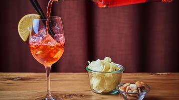 Aperol sendo vertido num copo com uma fatia de limão e gelo.