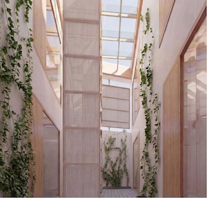 A narrow corridor with a skylight, wooden paneling, and climbing plants. - Baxter Hotel (Visp)