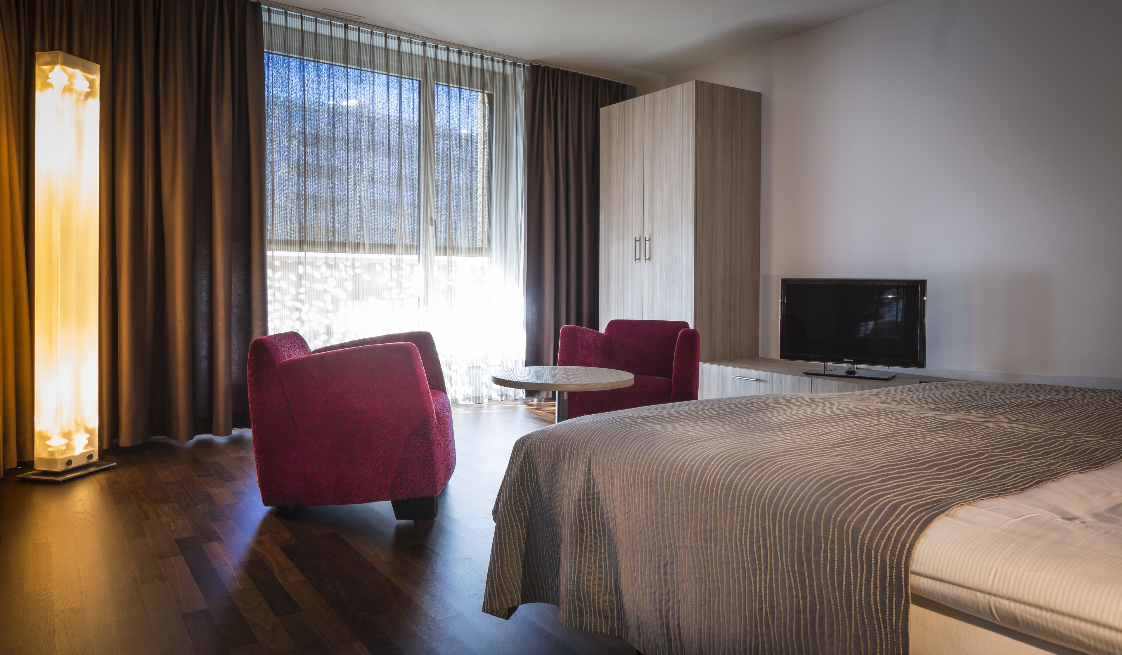 Une chambre d’hôtel avec un grand lit, une télévision, un bureau et deux chaises.