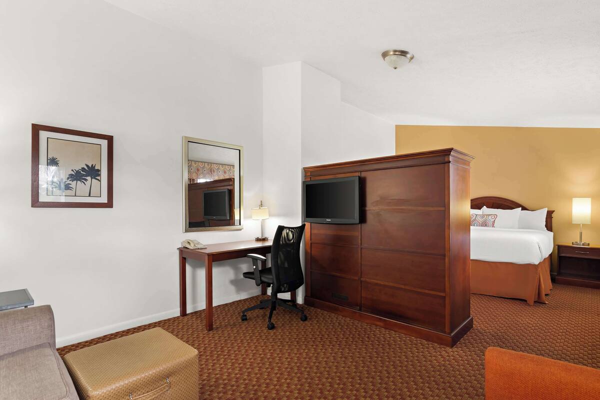 Une chambre d’hôtel comprenant un lit, un bureau avec une chaise, une télévision et une armoire.