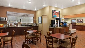 Una cocina de hotel con comedor, equipada con cafetera, microondas y diversos electrodomésticos.