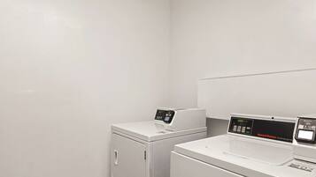 A laundry room with two white washing machines and a dryer.