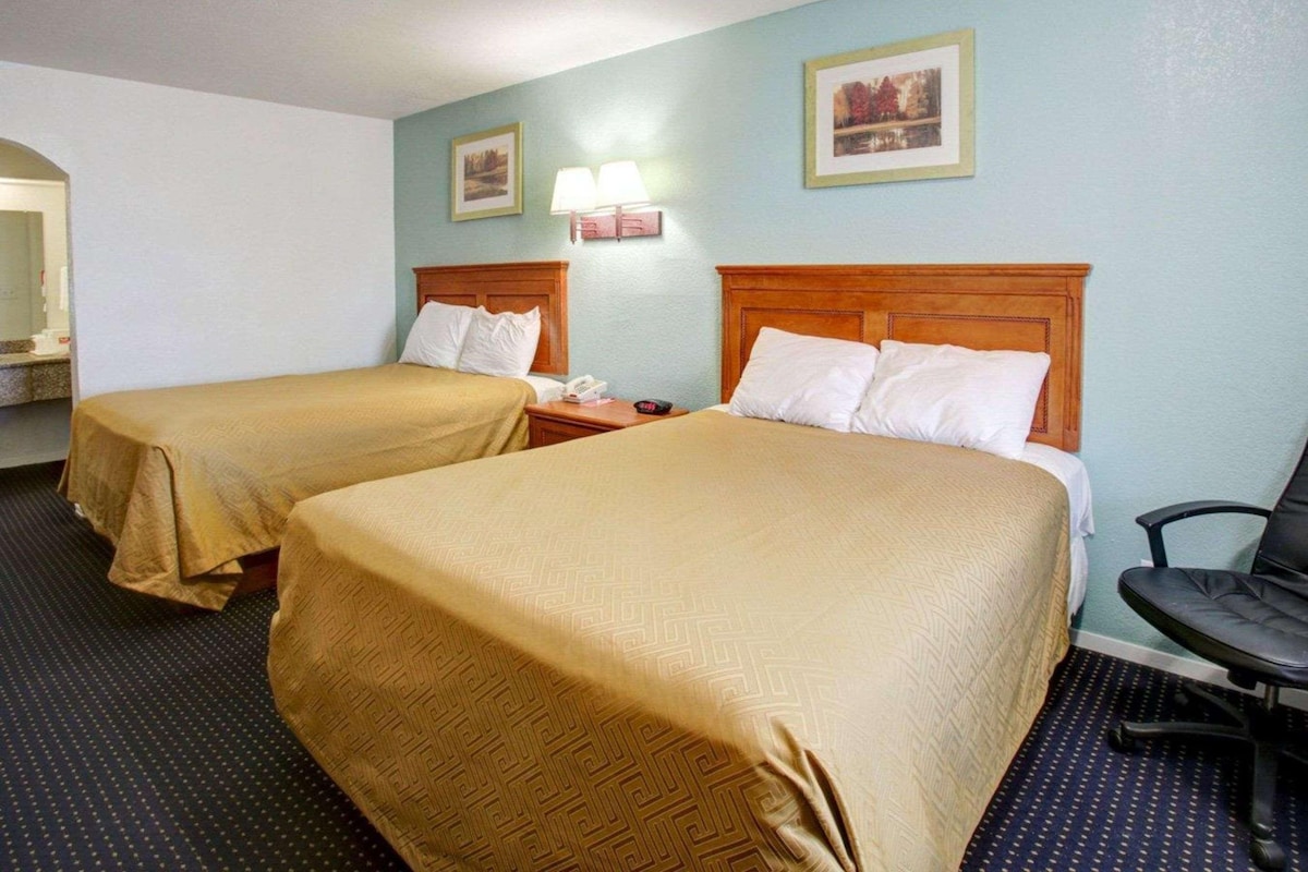Une chambre d’hôtel avec deux lits, un bureau et une chaise.