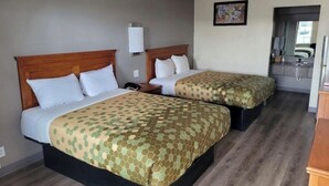 A hotel room with two beds, a small desk, a nightstand, a mirror, and a bathroom visible through an open door.