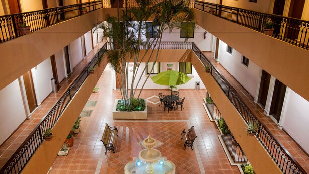 A multi-level atrium with a central fountain, potted plants, and seating areas. - Hotel Del Gobernador (Mérida)