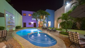 A swimming pool with lounge chairs and a building with a unique purple facade. - Hotel Del Gobernador (Mérida)