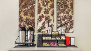 Una estación de café con una cafetera, tazas y una variedad de cápsulas de café.