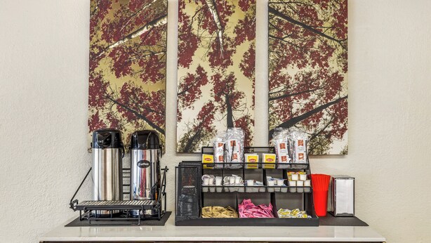 A coffee station with a coffee machine, cups, and a display of coffee pods. - Red Roof Inn Stroudsburg (Stroudsburg)