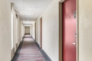 A hotel corridor with a patterned carpet, doors on both sides, and a red door on the right. - Red Roof Inn Stroudsburg (Stroudsburg)