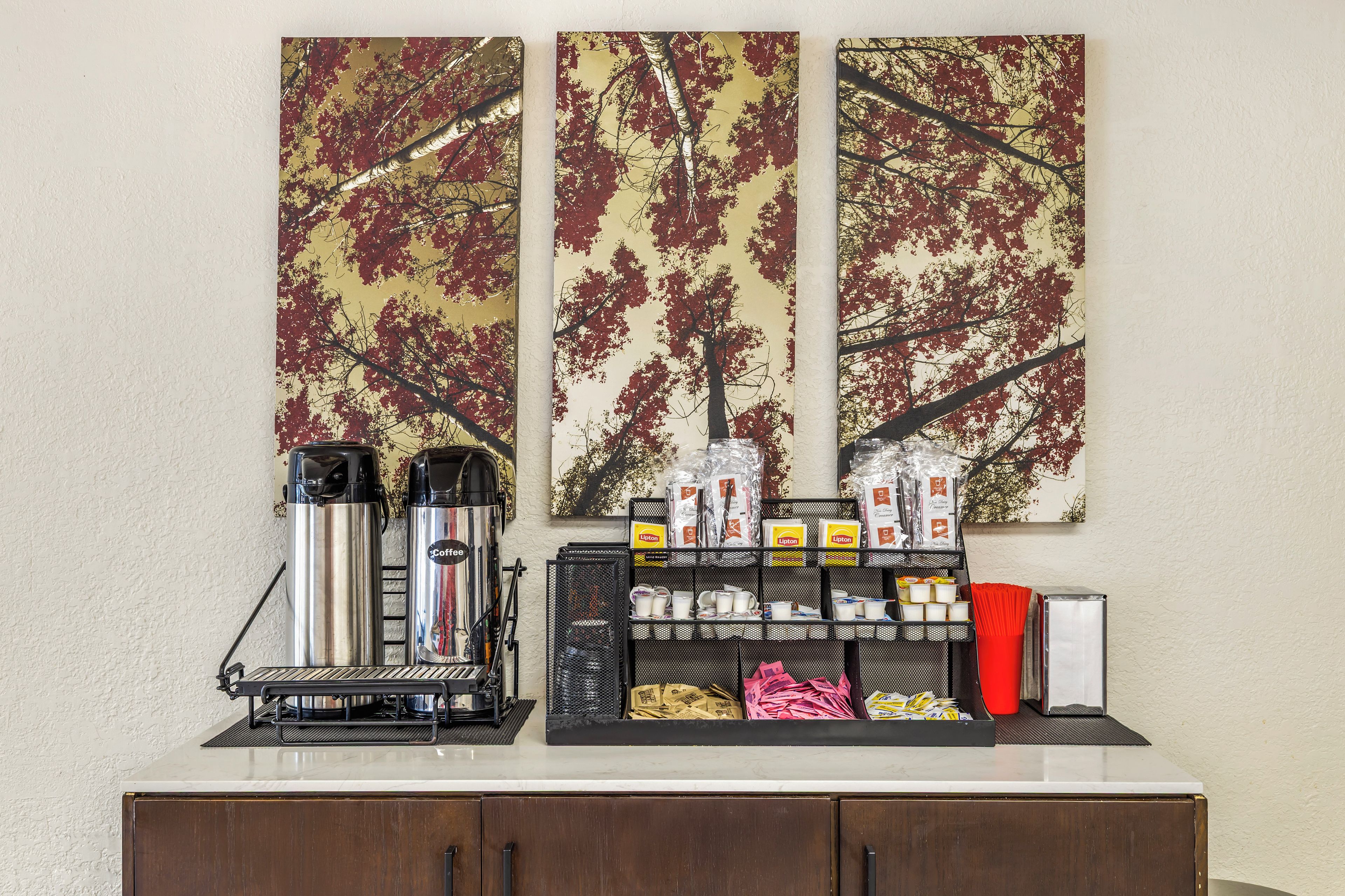 Un espace dédié au café, équipé de deux machines à café, d’un mousseur à lait et d’un assortiment de capsules de café et de petits pots de crème.