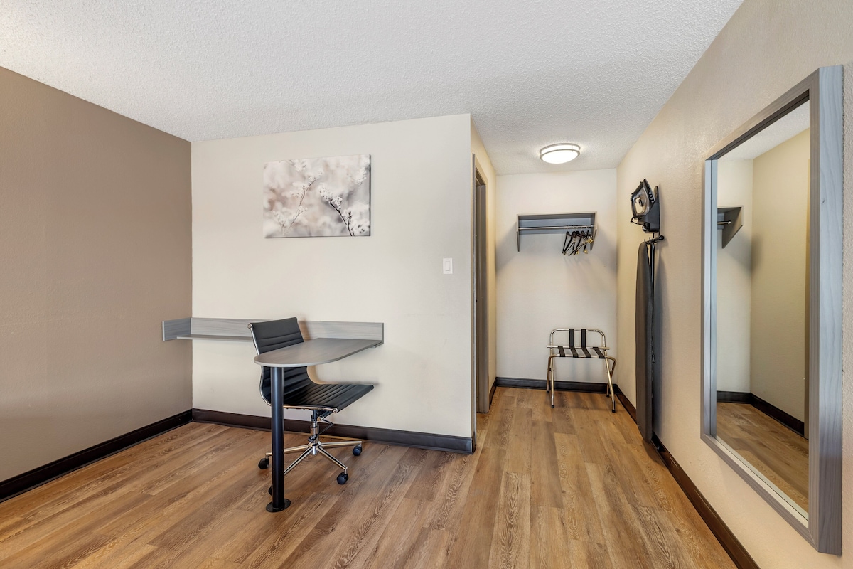 A hallway with a desk, chair, and artwork on the wall.
