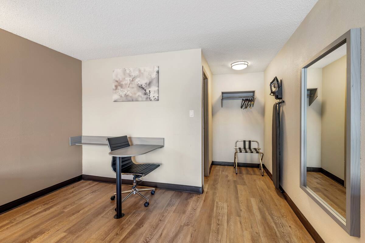A hallway with a desk, chair, and artwork on the wall.