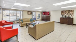 A lobby with beige sofas, red chairs, a coffee station, and a reception desk. - Red Roof Inn Stroudsburg (Stroudsburg)