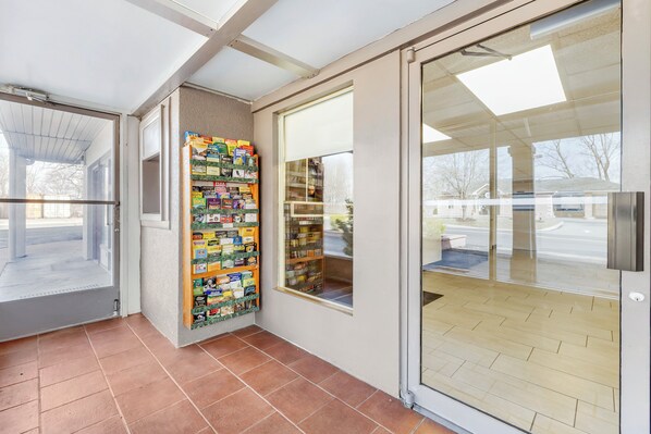A modern interior with a tiled floor, a glass door leading outside, and a wall-mounted bookcase filled with books. - Red Roof Inn Stroudsburg (Stroudsburg)