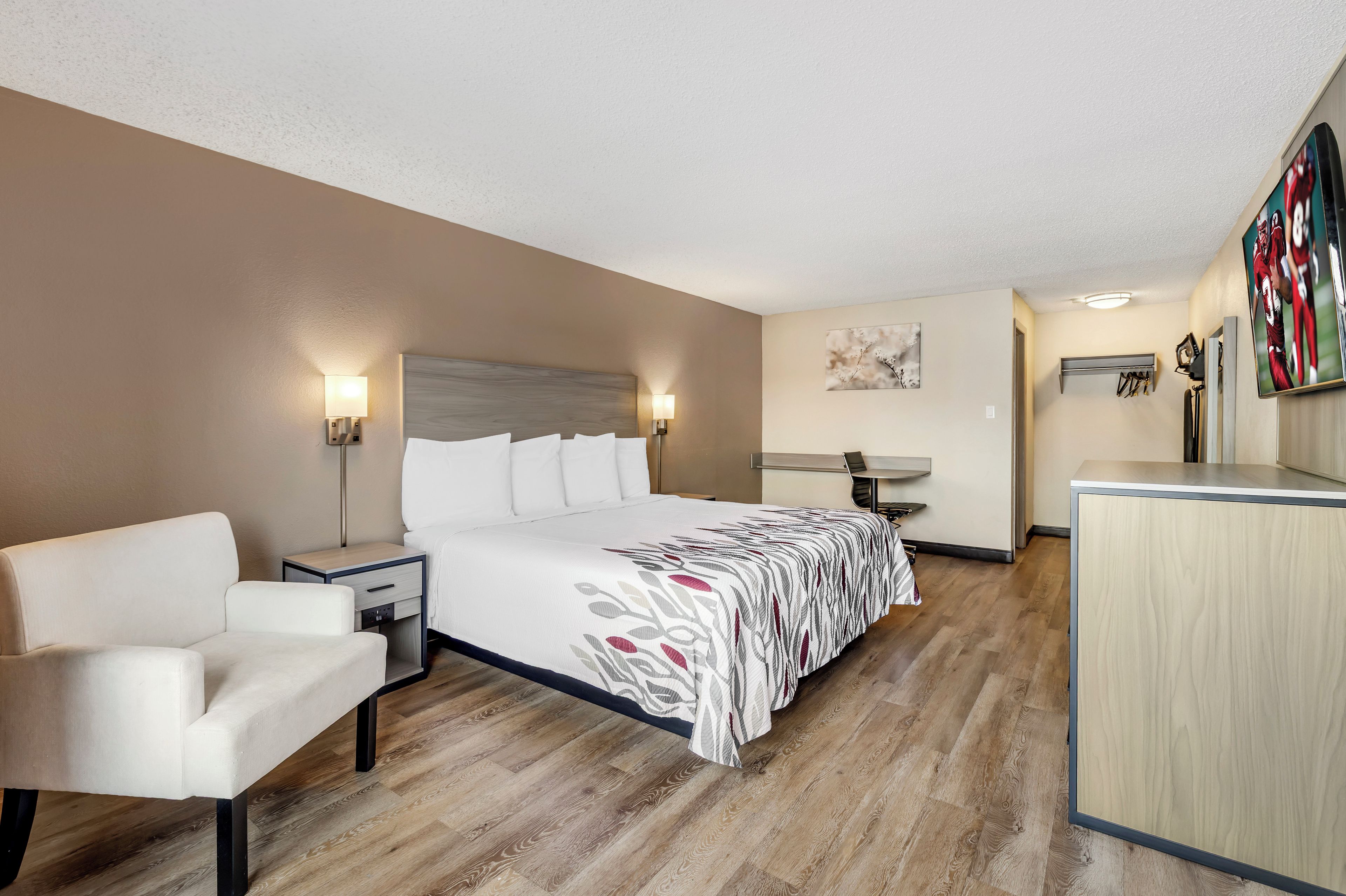Una habitación de hotel con una cama, un escritorio, una silla y un televisor.