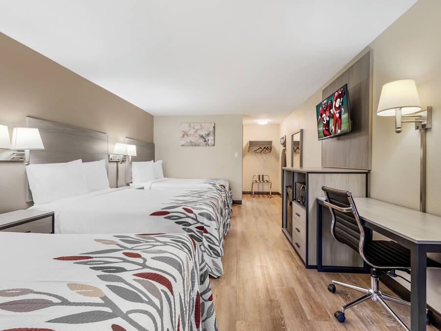 Una habitación de hotel con una cama grande, un escritorio, una silla, un televisor y una lámpara.