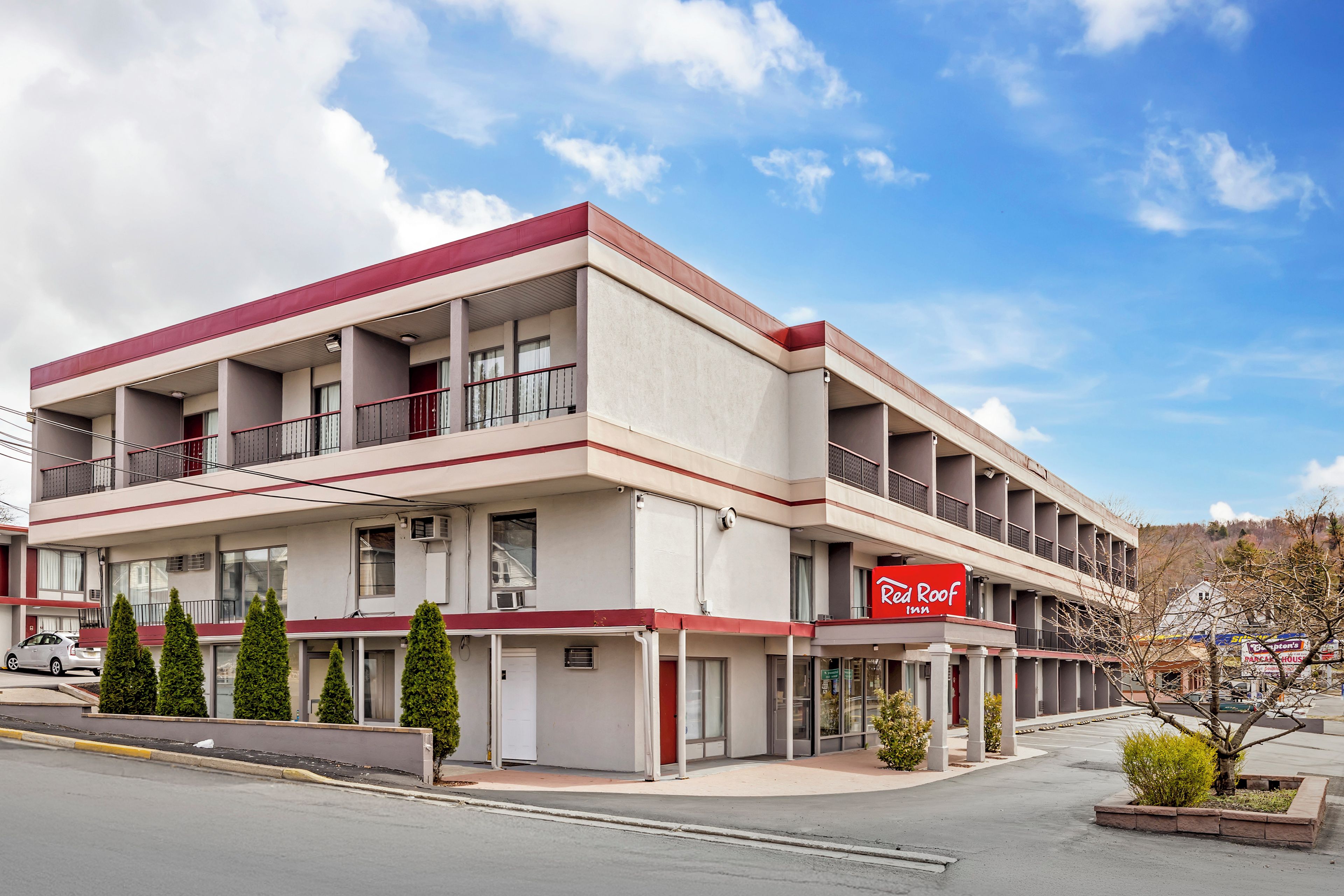 Un hotel de varios pisos con fachada roja y blanca, varios balcones y un cielo despejado.