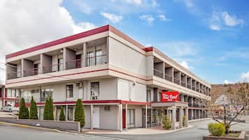 Un hotel de varios pisos con fachada roja y blanca, varios balcones y un cielo despejado.