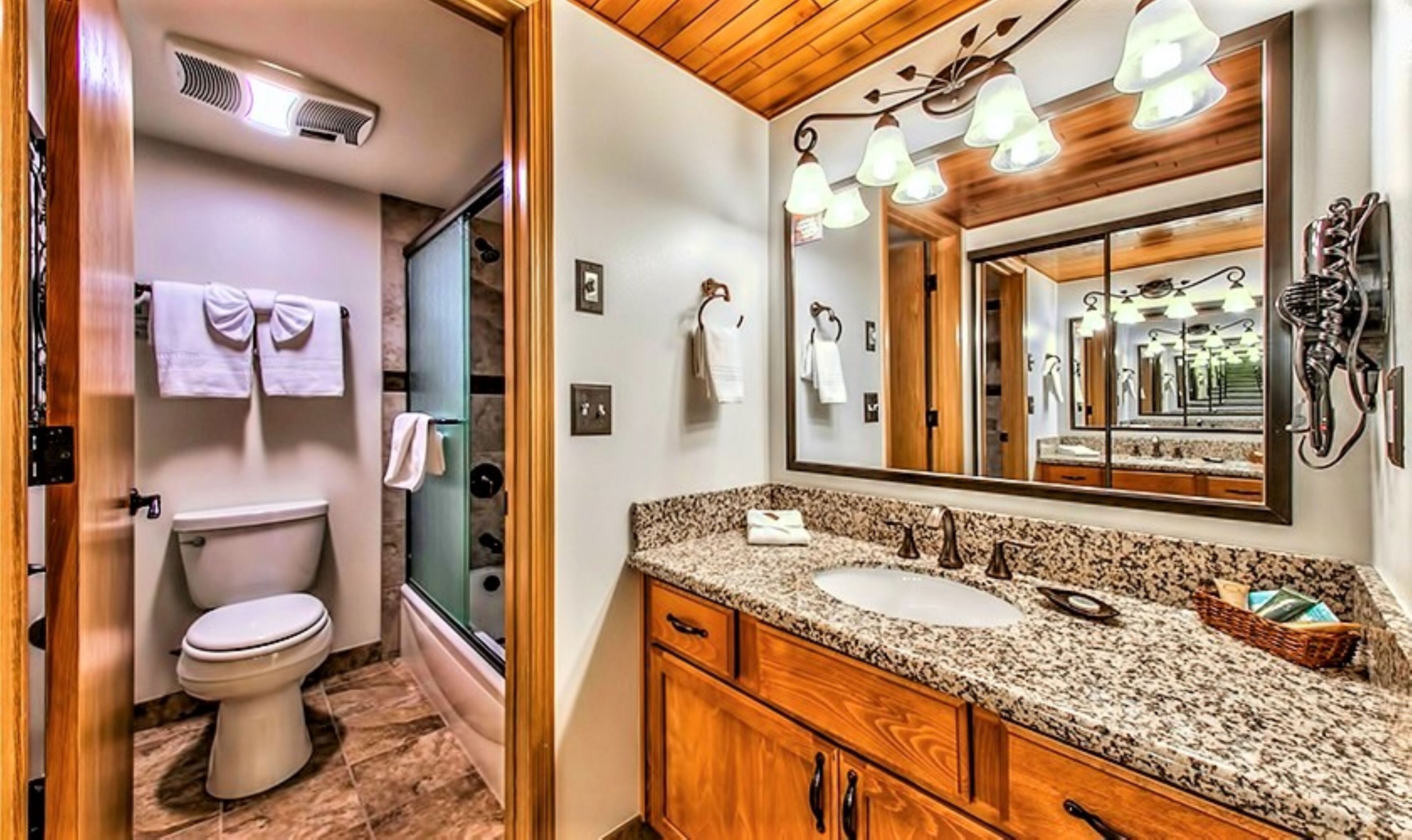 Une salle de bain comprenant des toilettes, une douche et un meuble-lavabo avec un évier et un miroir.