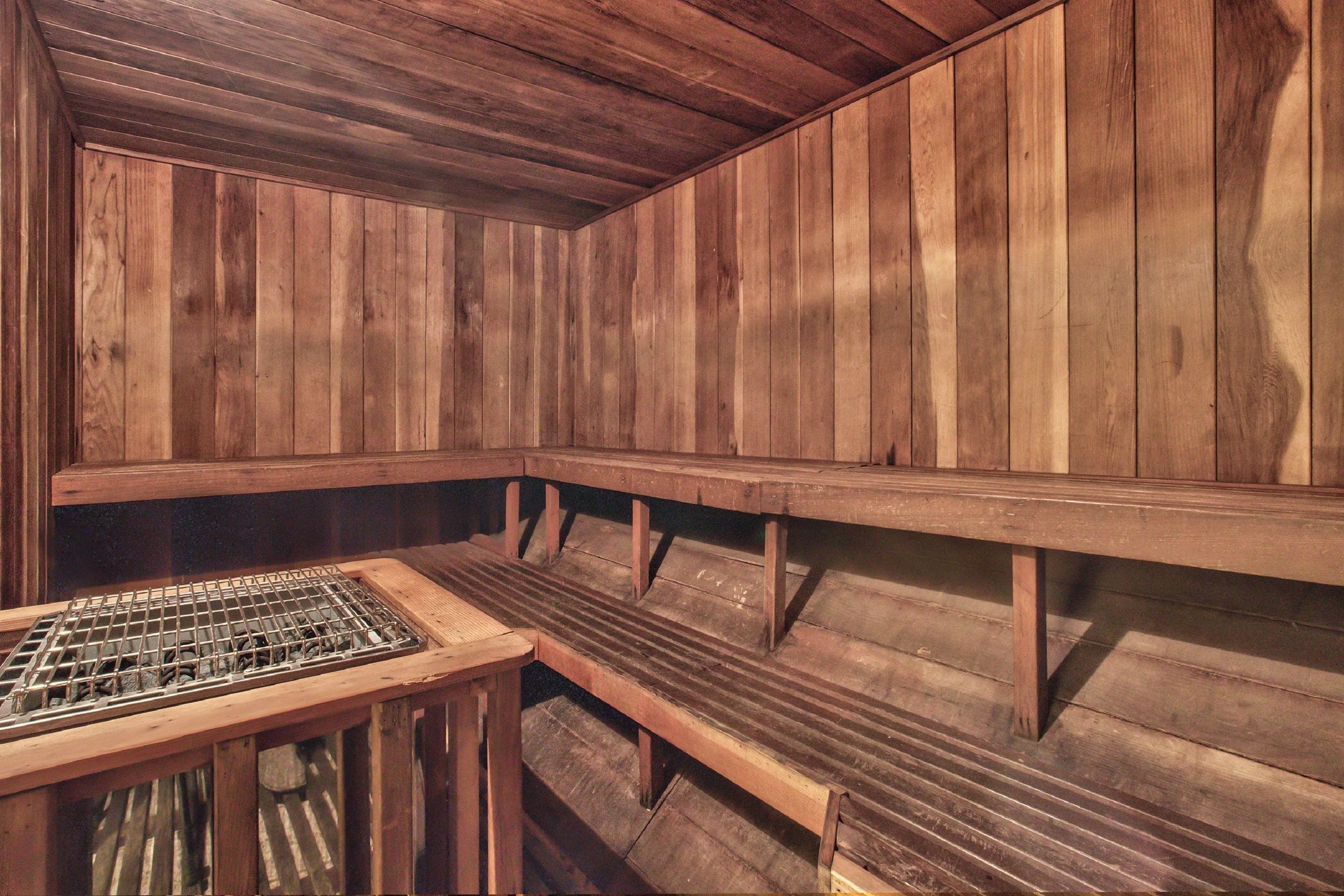 Una sauna con panche in legno e una griglia metallica.