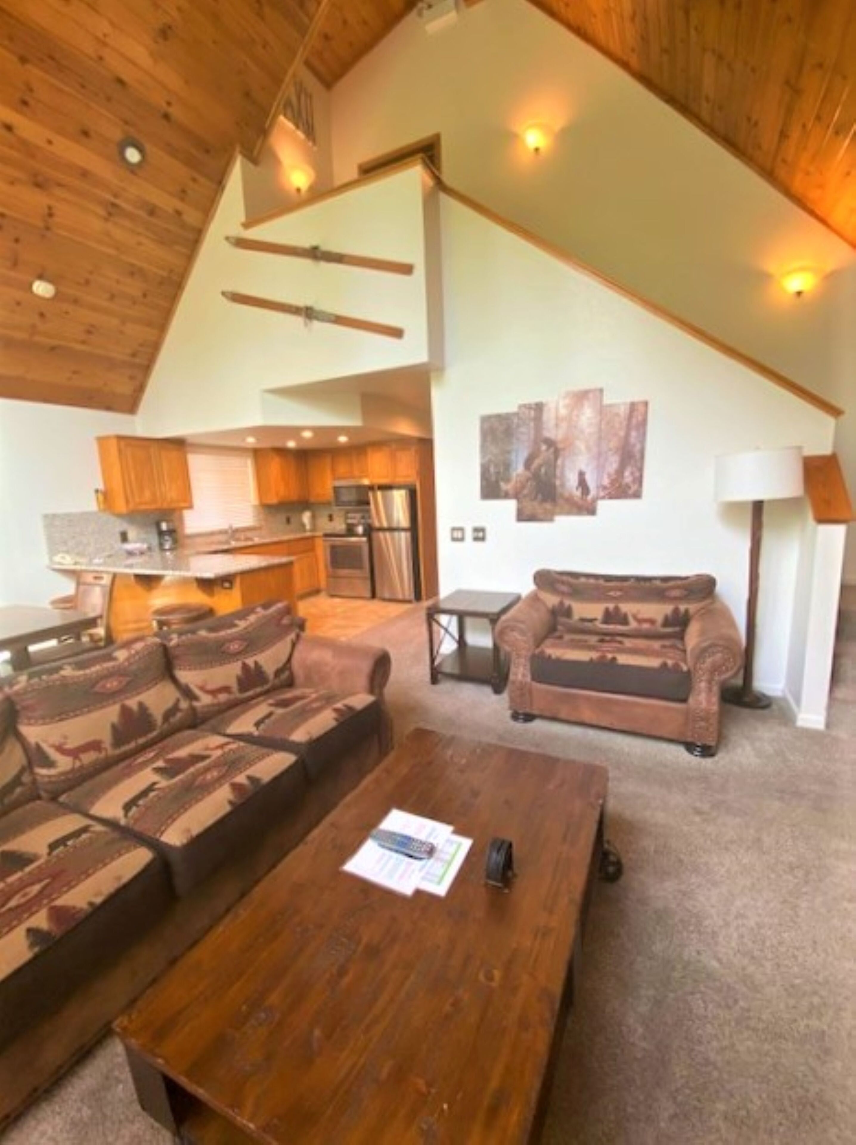 A spacious living area with a large sofa set, a wooden coffee table, and a kitchen in the background.