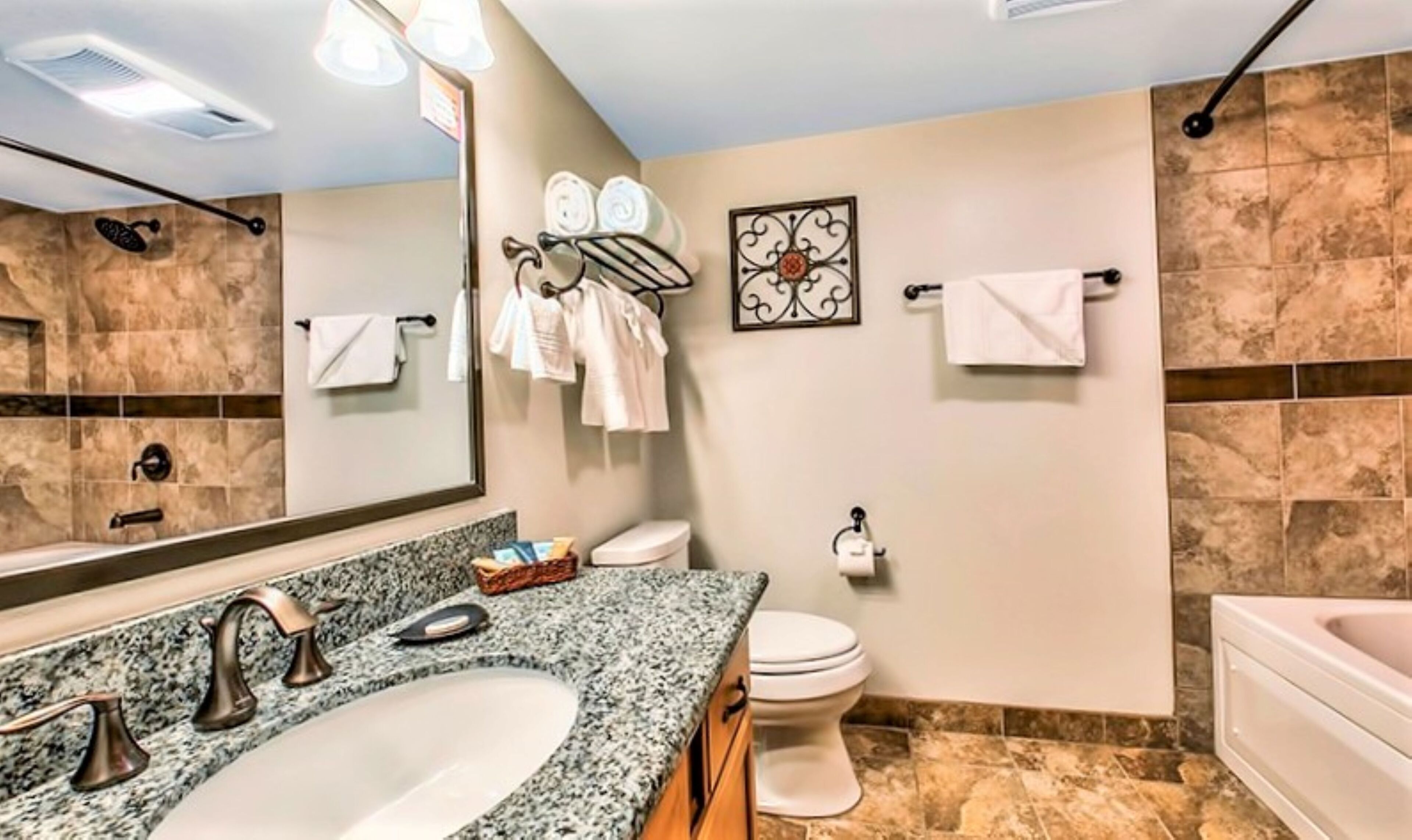 A bathroom with a granite countertop sink, a toilet, and a bathtub.