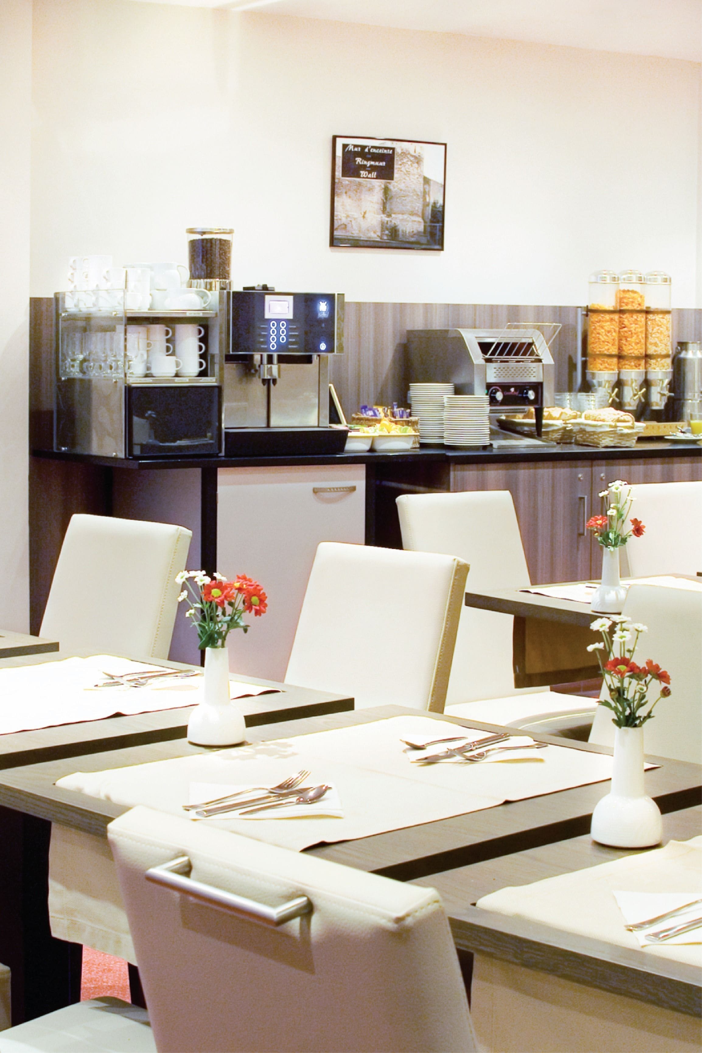 A dining area with tables set for meals, a coffee station, and a framed picture on the wall.