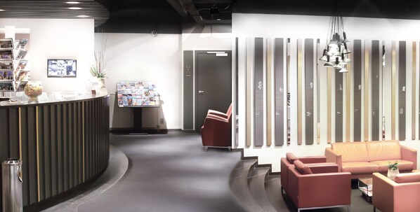 A reception area with a counter, seating, and a wall with vertical panels. - Atlas Hotel Brussels (Brussels)