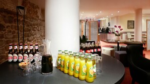 A bar area with bottles of Stella Artois beer, glasses, and a large bottle of wine. There are also bottles of orange juice and a variety of other beverages. - Atlas Hotel Brussels (Brussels)