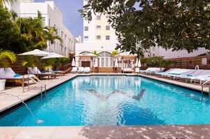 Una piscina al aire libre, camas de piscina con cargo, sombrillas