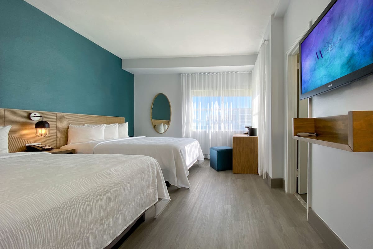 A hotel room with two beds, a television, a mirror, and a window with curtains.