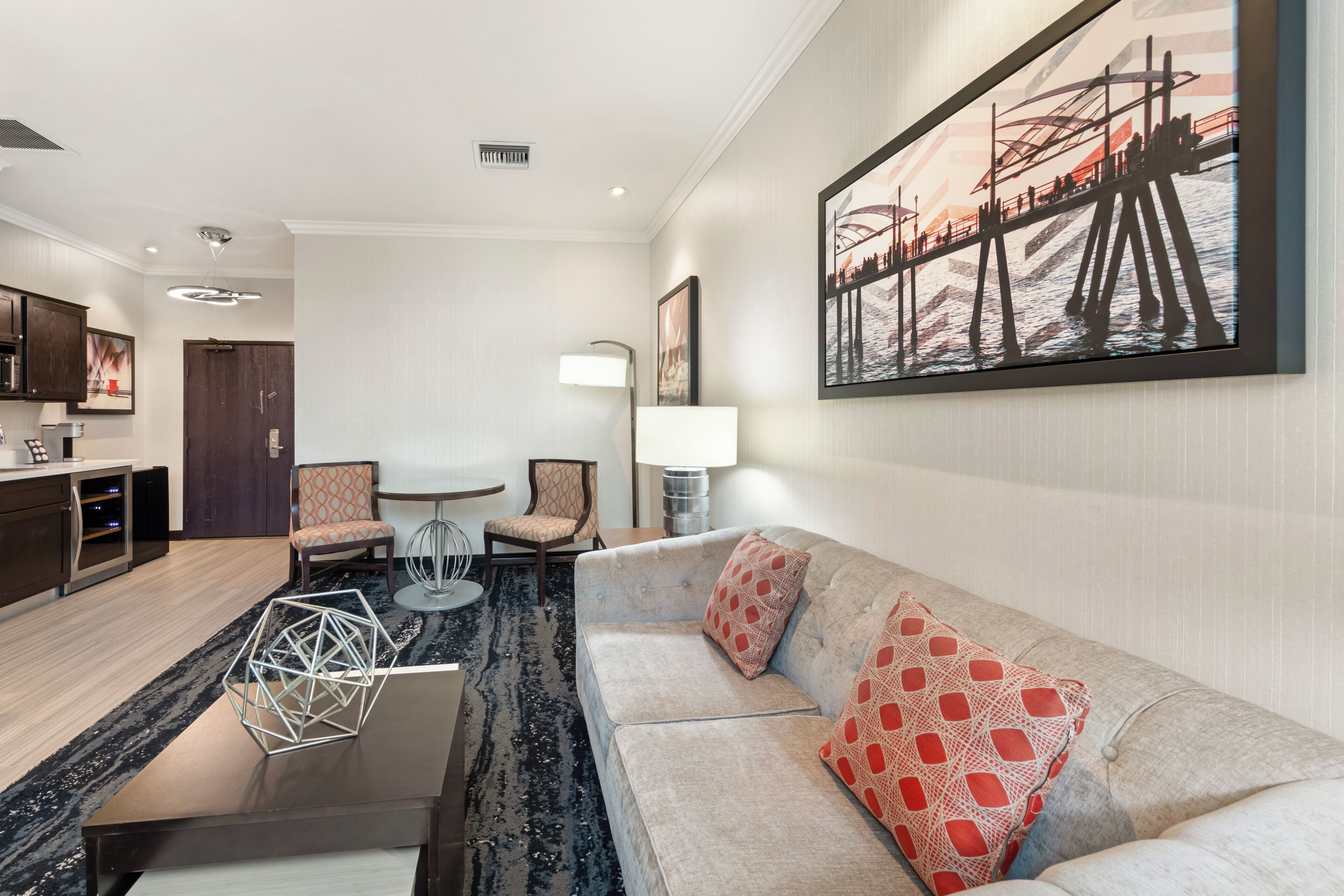 Una habitación de hotel moderna con sala de estar, comedor y un amplio ventanal con vistas a la ciudad.