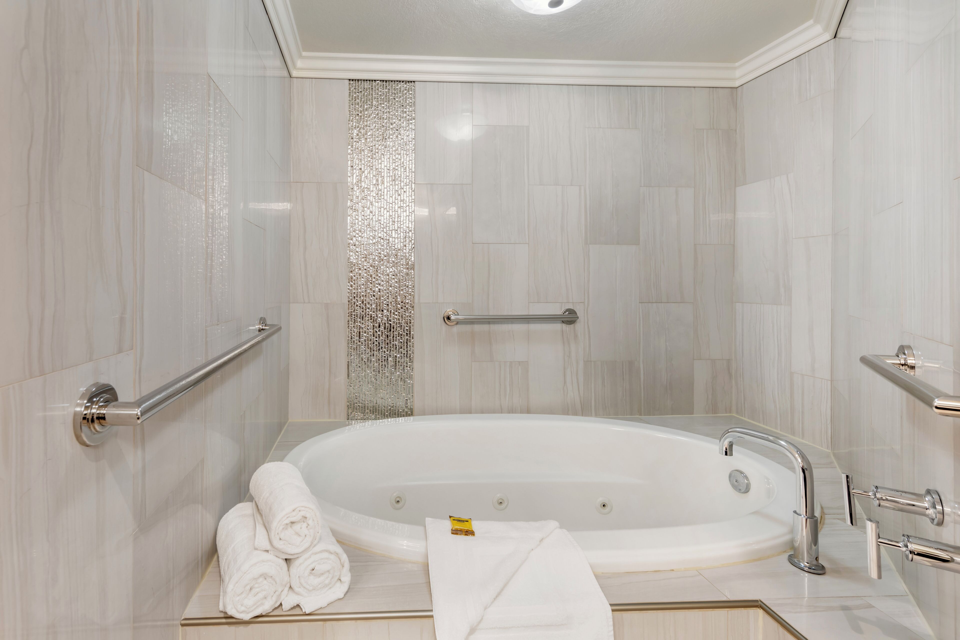 Une salle de bain moderne avec une baignoire sur pieds, des barres d’appui et un porte-serviettes.