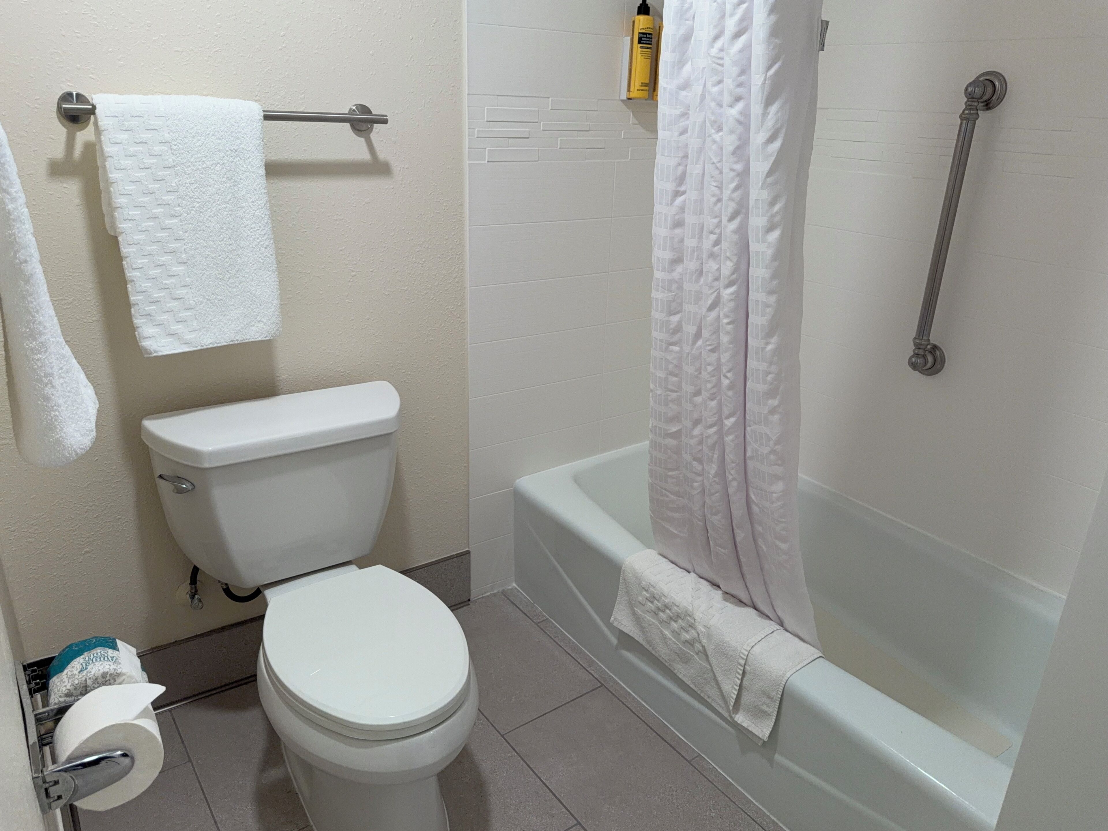 Une salle de bain équipée de toilettes, d’une baignoire et d’un rideau de douche.