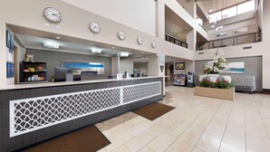A hotel reception area with a counter, clocks, a coffee machine, and a decorative plant. - Best Western Plus Redondo Beach Inn (Redondo Beach)