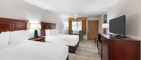 A hotel room with two beds, a desk, a chair, a television, and a door.